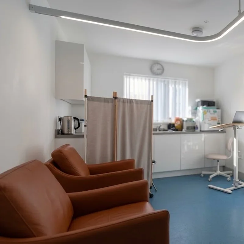 A treatment room at the clinic: leather armchairs, a privacy screen and a sunlit window